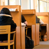 People sitting at wooden study carrels