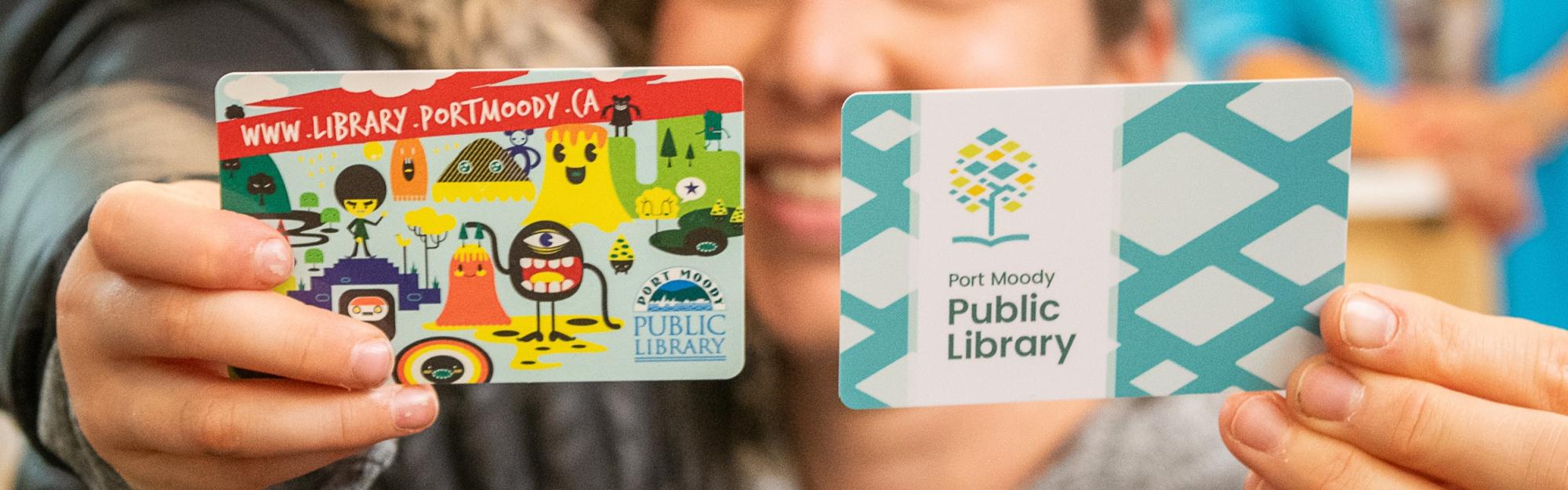 Mother and child holding up library cards to the camera and smiling